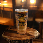 Glass of iced coffee with 'Jack Daniel's Tennessee Honey' branding on a wooden surface in a dimly lit bar.
